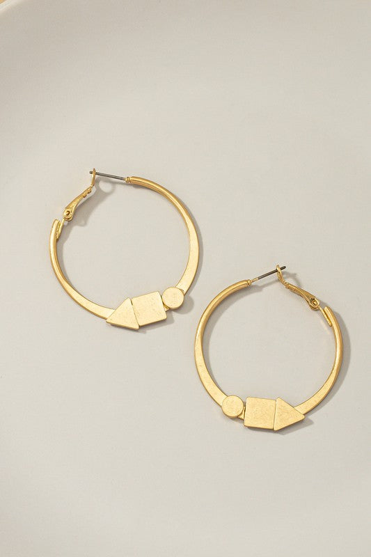 Two flat hoop earrings with intricate designs from the Geo shapes collection rest on a smooth, light surface.