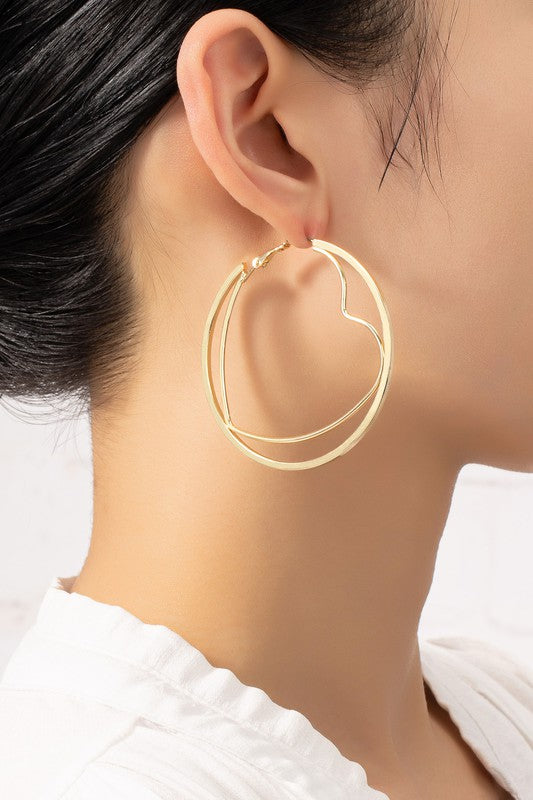 The heart hoop inside a circle hoop earrings, featuring shiny gold plating, are exquisitely presented on a light-colored plate.