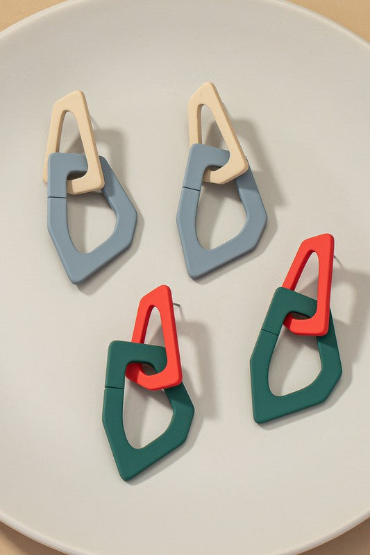 Close-up of lightweight acrylic earrings named "Organic Shape Chunky Link Drop Earrings," featuring interlocking triangular shapes in beige and gray, displayed on a flat surface.