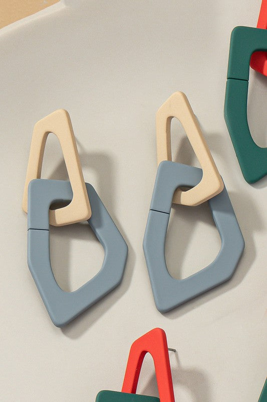 Close-up of lightweight acrylic earrings named "Organic Shape Chunky Link Drop Earrings," featuring interlocking triangular shapes in beige and gray, displayed on a flat surface.