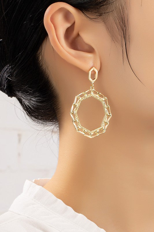 The Octagon chunky link chain hoop drop earrings, gold-plated with a geometric design, are elegantly displayed on a white surface.