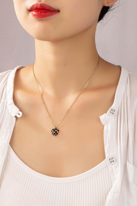 Introducing the Checker Heart Pendant Necklace: A collection of five necklaces showcasing a chic style with heart-shaped pendants. Each pendant features elegant enamel designs in pink, blue, white, and black on a beige background, adding a touch of sophistication to your ensemble.