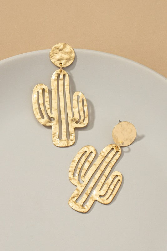 Four pairs of hammered thin metal openwork cactus drop earrings, two in matte gold and two in silver, elegantly arranged on a neutral surface.