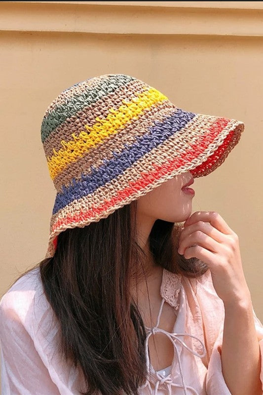 Three vibrant Packable crochet straw bucket hats with multi-color stripes are stacked elegantly on a plain background.