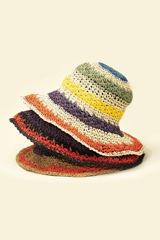 Three vibrant Packable crochet straw bucket hats with multi-color stripes are stacked elegantly on a plain background.