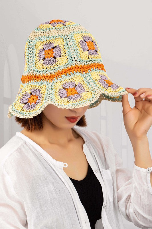 This packable crochet granny square bucket hat showcases exquisite hand-crocheted craftsmanship with a colorful pattern in shades of yellow, orange, and purple on a light background.