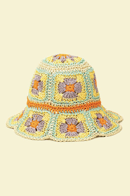 This packable crochet granny square bucket hat showcases exquisite hand-crocheted craftsmanship with a colorful pattern in shades of yellow, orange, and purple on a light background.