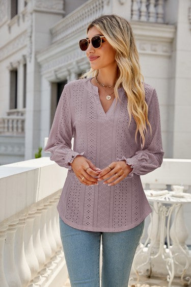 A woman wearing sunglasses, a light pink Women Long Sleeve TOP, and blue jeans stands on a balcony.