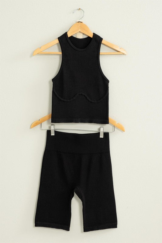 The Power Move Cropped Tank Top and Biker Shorts Set hangs on a wooden hanger against a white background, making it the perfect workout apparel.