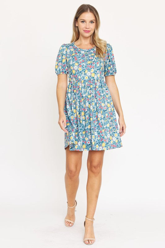 Woman wearing a Gathered Puff Sleeve Mini Dress in blue floral, made with a Polyester Spandex blend, standing against a plain white background.