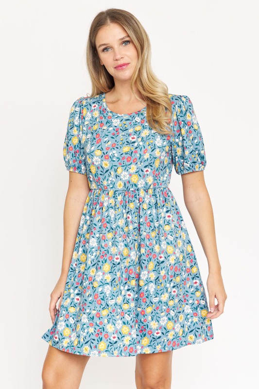 Woman wearing a Gathered Puff Sleeve Mini Dress in blue floral, made with a Polyester Spandex blend, standing against a plain white background.