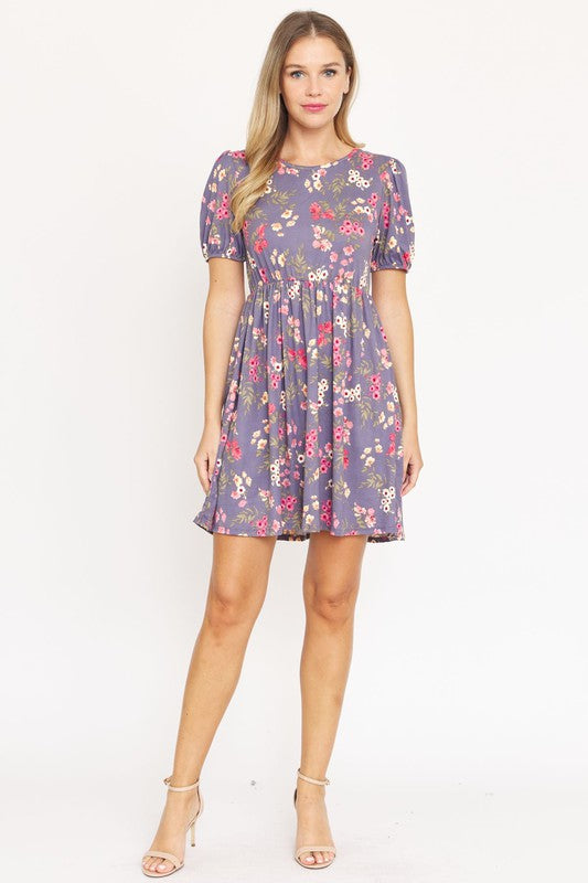 Woman wearing a Gathered Puff Sleeve Mini Dress in blue floral, made with a Polyester Spandex blend, standing against a plain white background.