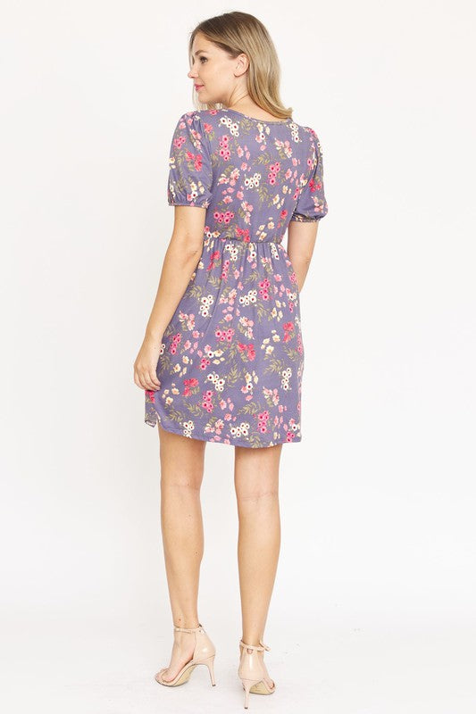 Woman wearing a Gathered Puff Sleeve Mini Dress in blue floral, made with a Polyester Spandex blend, standing against a plain white background.