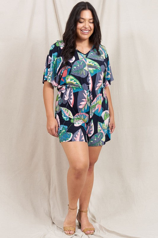 A person wearing a Plus Tropical Kimono Sleeve Romper is smiling, standing against a neutral background.