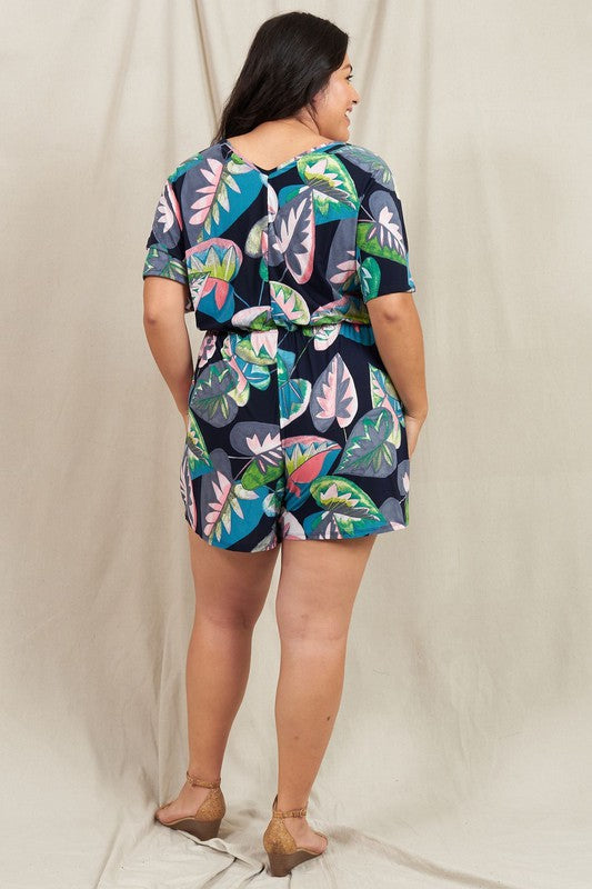 A person wearing a Plus Tropical Kimono Sleeve Romper is smiling, standing against a neutral background.