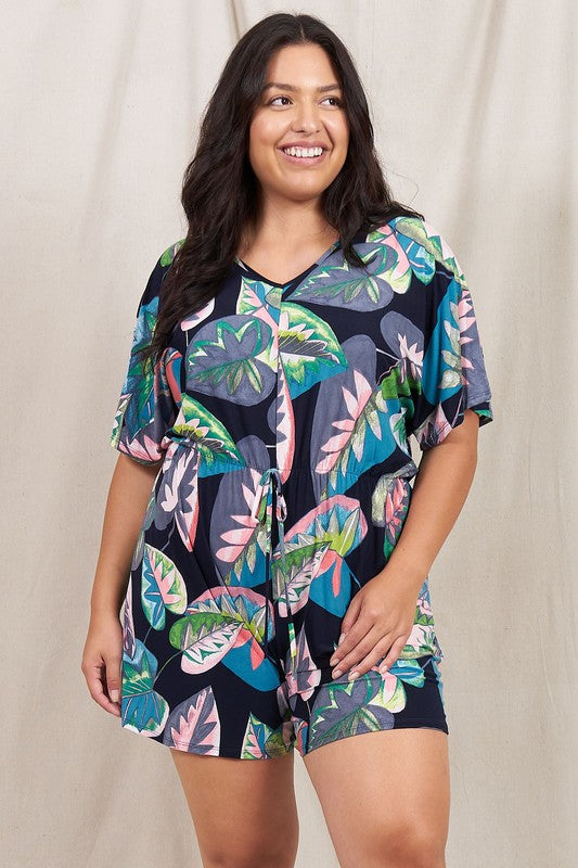 A person wearing a Plus Tropical Kimono Sleeve Romper is smiling, standing against a neutral background.