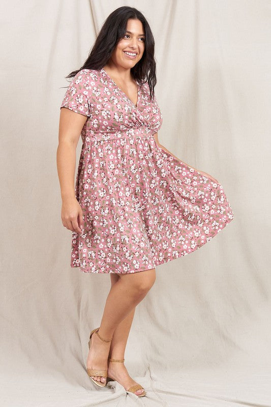 A person wearing a Plus Ditsy Surplice Fit and Flare Midi Dress stands in front of a beige curtain, smiling warmly.