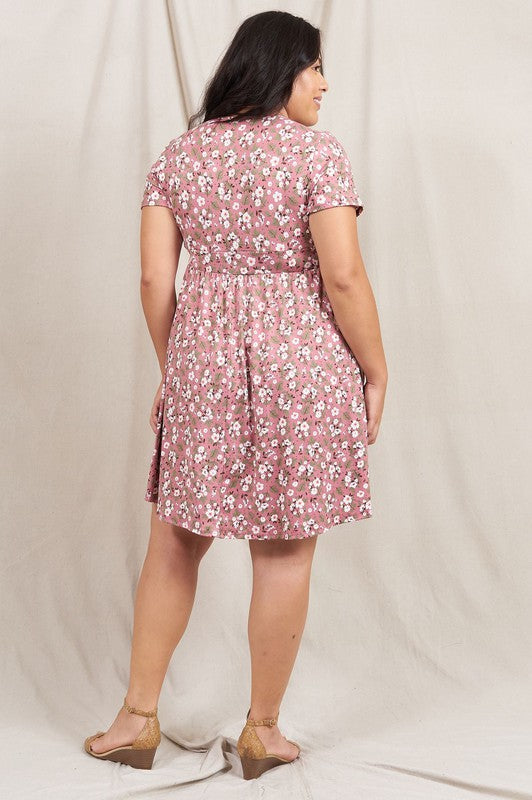 A person wearing a Plus Ditsy Surplice Fit and Flare Midi Dress stands in front of a beige curtain, smiling warmly.