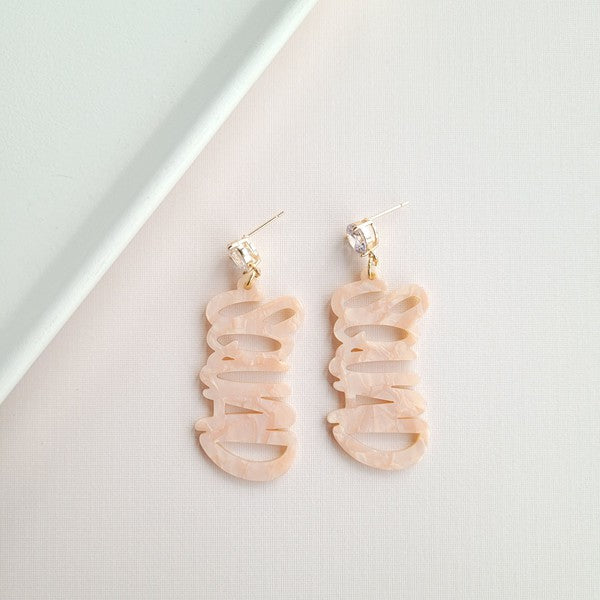 Two dangling earrings featuring "chaos" in peach-colored material, with exquisite hand-lettered calligraphy, are attached to gold posts adorned with clear stone accents. Perfectly named the "Bachelorette Squad," these earrings make a stunning bridal party gift and rest elegantly on a white surface.