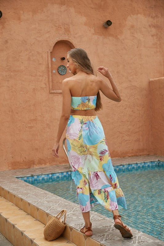 A woman wearing a colorful floral Womens 2pcs Long Skirt Set and a straw hat walks down outdoor steps holding a woven handbag.