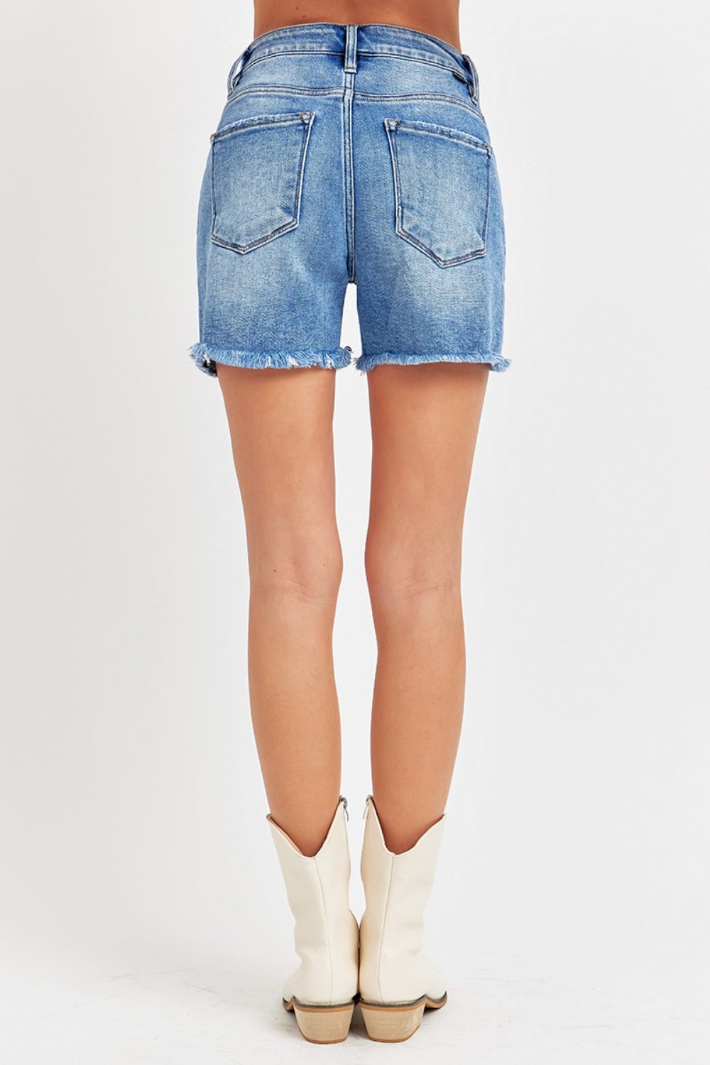 Close-up of a person wearing RISEN Front Slit Raw Hem Denim Shorts.