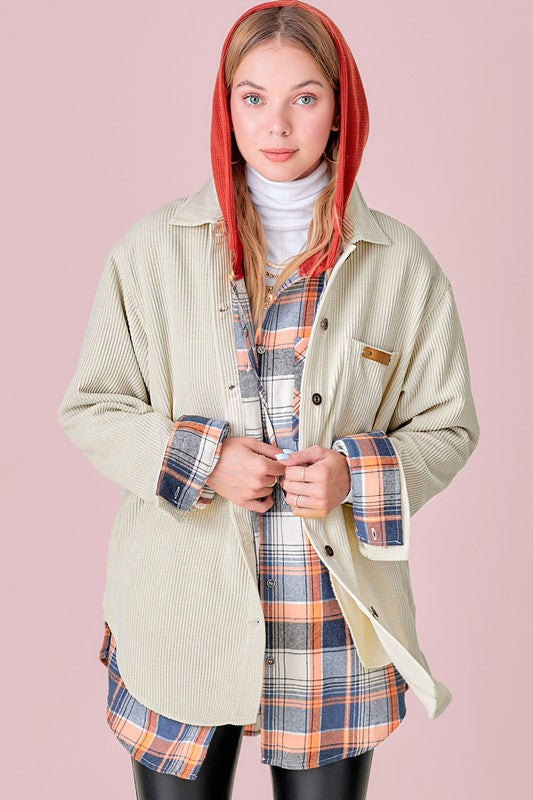 A person wearing a pink Chaser Madera Cozy Button Down Shacket, black pants, and a beige hat stands against a pastel-colored background, showcasing a casual chic look.
