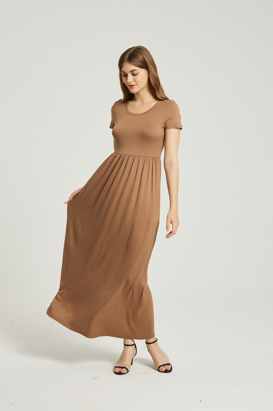 A woman in a Women's Summer Casual Maxi Dress With Pocket and black sandals stands against a plain background. Holding the skirt of her A-line dress, she exudes effortless style.