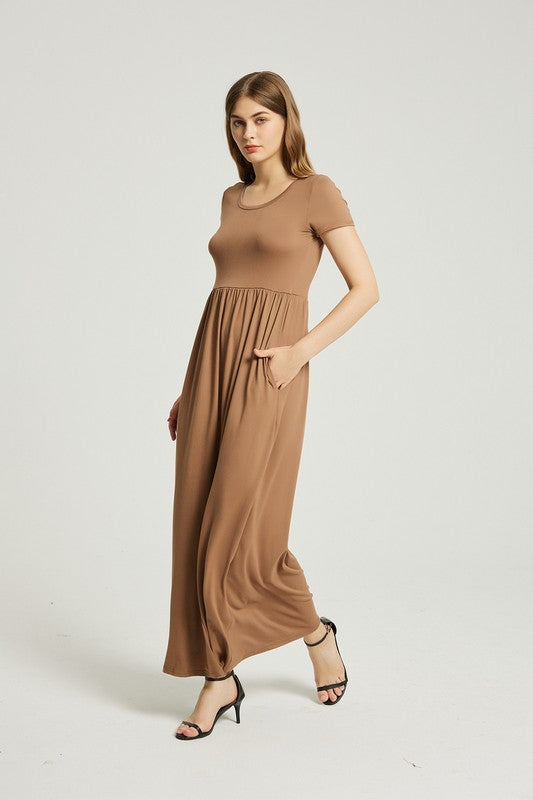 A woman in a Women's Summer Casual Maxi Dress With Pocket and black sandals stands against a plain background. Holding the skirt of her A-line dress, she exudes effortless style.