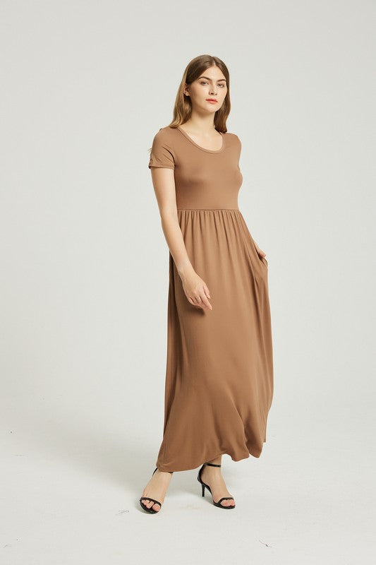 A woman in a Women's Summer Casual Maxi Dress With Pocket and black sandals stands against a plain background. Holding the skirt of her A-line dress, she exudes effortless style.