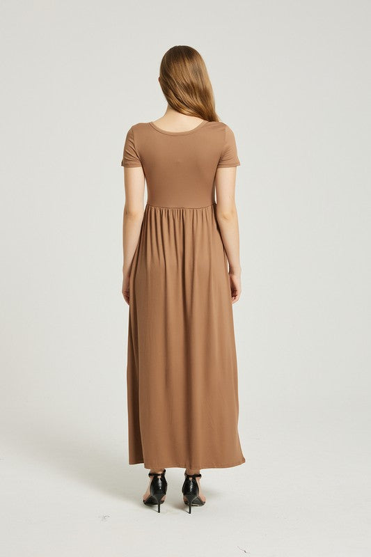 A woman in a Women's Summer Casual Maxi Dress With Pocket and black sandals stands against a plain background. Holding the skirt of her A-line dress, she exudes effortless style.