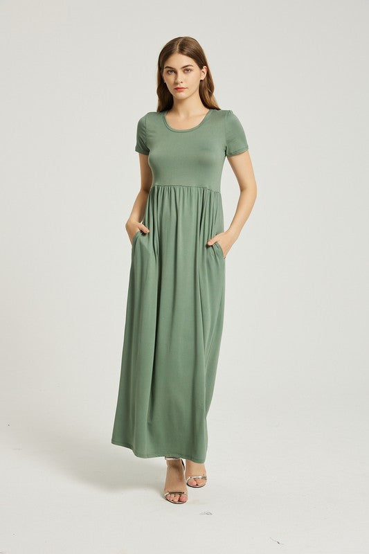 A woman wearing a Women's Summer Casual Maxi Dress With Pocket in green is seated on a white chair against a plain background.