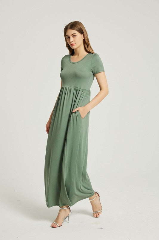 A woman wearing a Women's Summer Casual Maxi Dress With Pocket in green is seated on a white chair against a plain background.