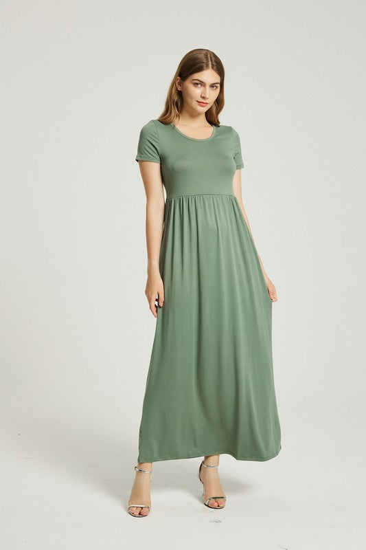 A woman wearing a Women's Summer Casual Maxi Dress With Pocket in green is seated on a white chair against a plain background.