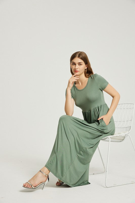 A woman wearing a Women's Summer Casual Maxi Dress With Pocket in green is seated on a white chair against a plain background.