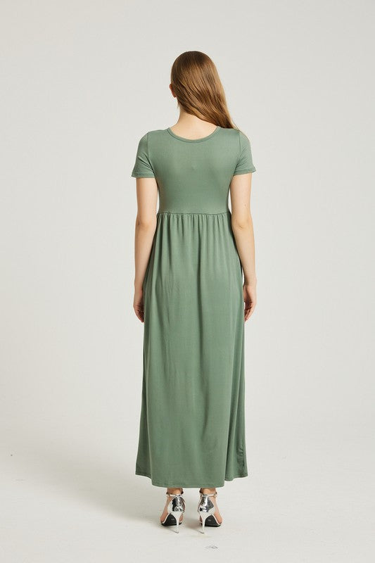 A woman wearing a Women's Summer Casual Maxi Dress With Pocket in green is seated on a white chair against a plain background.