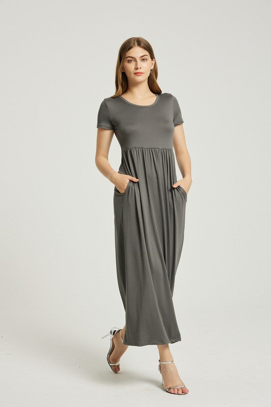 A woman in a grey Women's Summer Casual Maxi Dress With Pocket, featuring an A-line silhouette and chic pocket style, stands with her hands in her pockets against a plain background. She is wearing light-colored sandals.