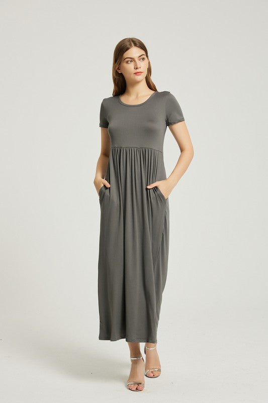A woman in a grey Women's Summer Casual Maxi Dress With Pocket, featuring an A-line silhouette and chic pocket style, stands with her hands in her pockets against a plain background. She is wearing light-colored sandals.