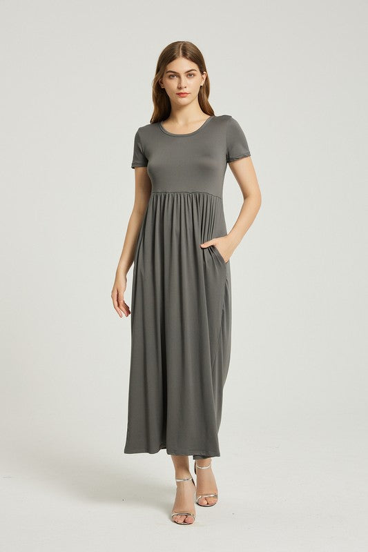 A woman in a grey Women's Summer Casual Maxi Dress With Pocket, featuring an A-line silhouette and chic pocket style, stands with her hands in her pockets against a plain background. She is wearing light-colored sandals.