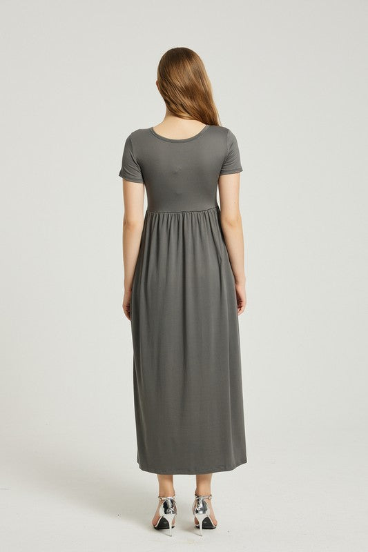 A woman in a grey Women's Summer Casual Maxi Dress With Pocket, featuring an A-line silhouette and chic pocket style, stands with her hands in her pockets against a plain background. She is wearing light-colored sandals.