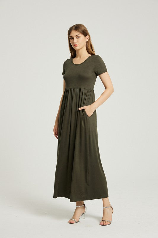 A person with straight hair is wearing a short-sleeved, floor-length dark green Women's Summer Casual Maxi Dress With Pocket and beige high-heeled sandals. They are standing against a plain white background.