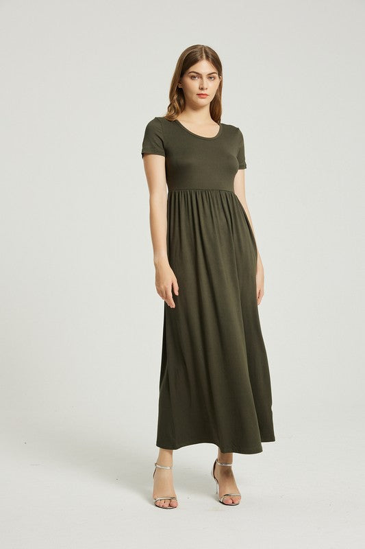 A person with straight hair is wearing a short-sleeved, floor-length dark green Women's Summer Casual Maxi Dress With Pocket and beige high-heeled sandals. They are standing against a plain white background.