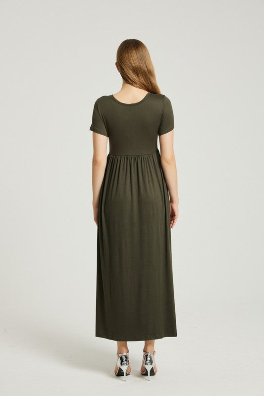 A person with straight hair is wearing a short-sleeved, floor-length dark green Women's Summer Casual Maxi Dress With Pocket and beige high-heeled sandals. They are standing against a plain white background.