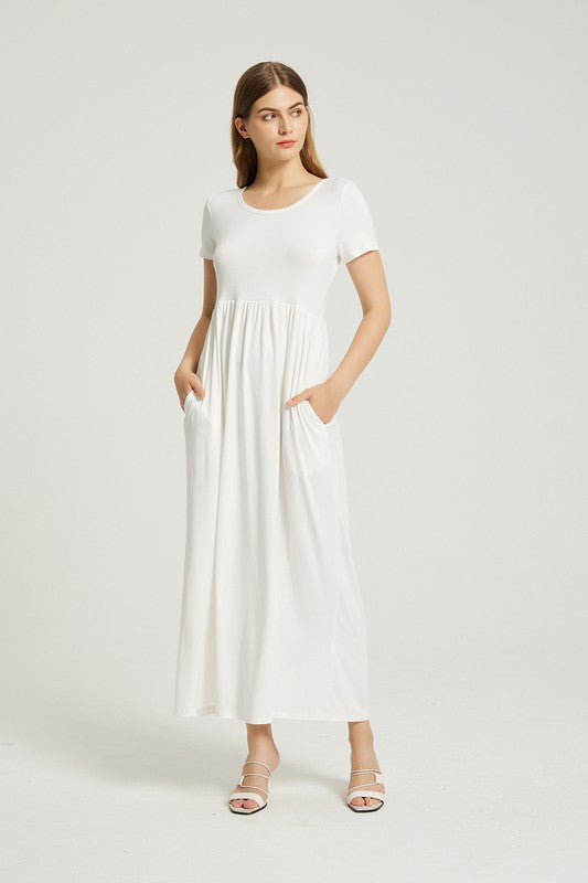 A woman in a white, short-sleeve, ankle-length Women's Summer Casual Maxi Dress With Pocket poses against a plain background. She is wearing white open-toed heels.