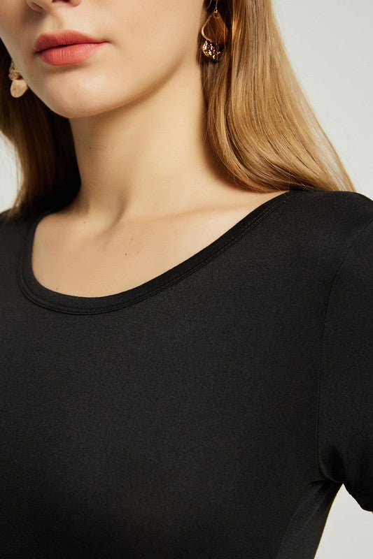 A woman with long brown hair is wearing a black Women's Summer Casual Maxi Dress With Pocket and black strappy sandals while walking. The backdrop is plain and light-colored.