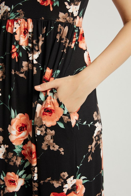 A woman sits in a wooden chair wearing a Womens Summer Casual Floral Maxi Dress With Pocket and black heels, with her left elbow resting on the armrest and her left hand touching her chin.