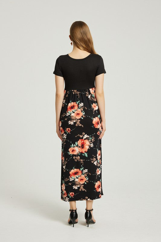 A woman stands with hands in pockets, wearing a Women's Summer Casual Floral Maxi Dress With Pocket featuring black and red floral patterns. She has long hair and is sporting black heeled sandals.