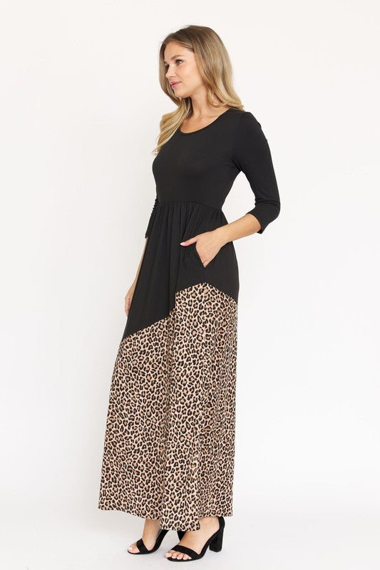 A woman wearing an Asymmetrical Leopard Accent Maxi Dress, made from polyester and featuring convenient pockets, stands against a plain white background.