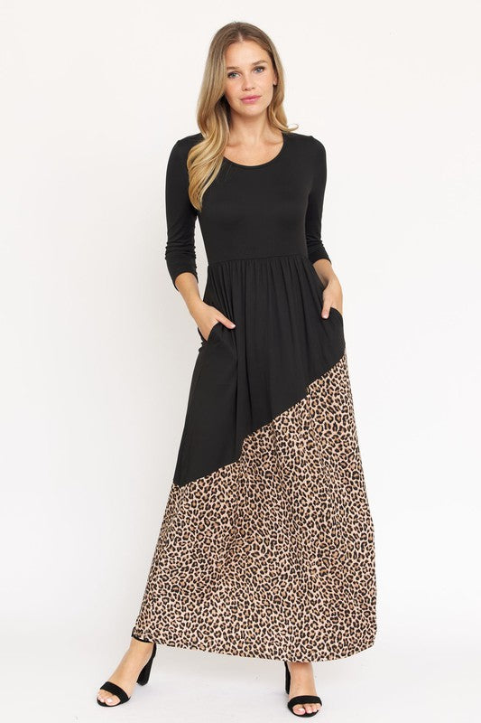 A woman wearing an Asymmetrical Leopard Accent Maxi Dress, made from polyester and featuring convenient pockets, stands against a plain white background.