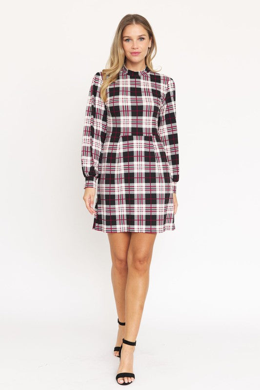 A woman stands smiling, wearing the High Neck Plaid Sheath Dress featuring a classic United States style in black, white, and red plaid with long sleeves.