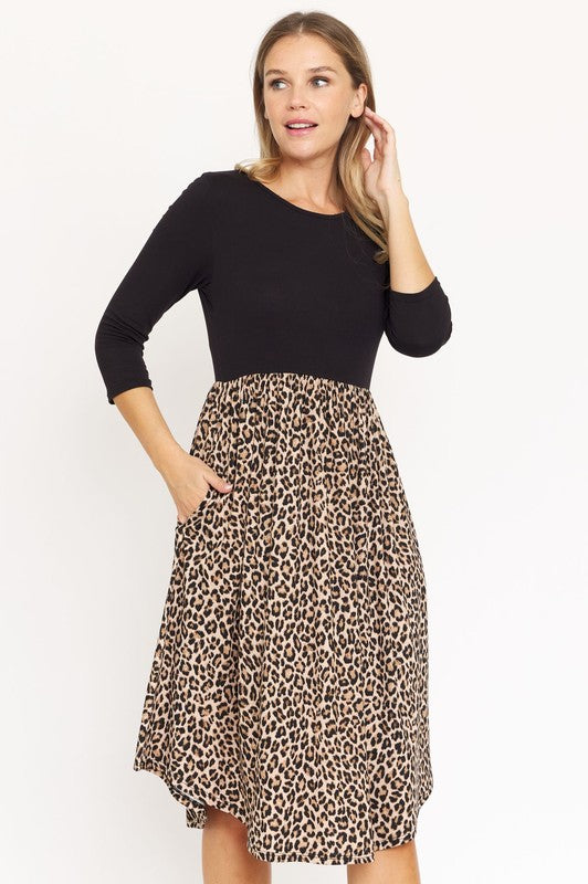 A woman in a fashionable Quarter Sleeve Midi Dress poses against a plain background, showcasing its elegant leopard print.